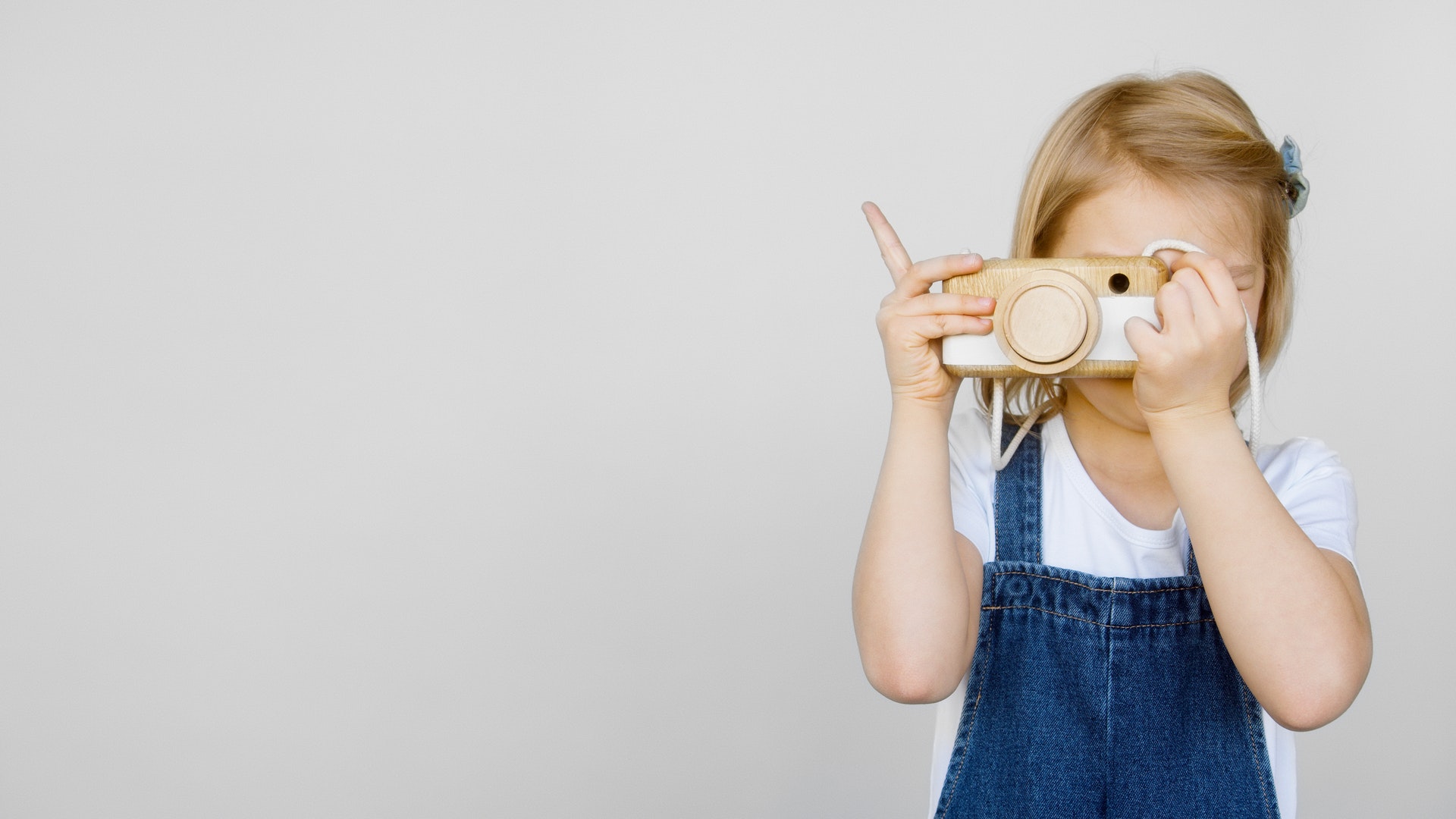 Child holding wooden camera for Children's Ministry